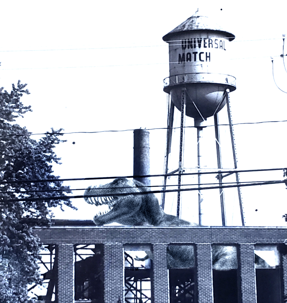 black and white image of a water tower in the background, a t-rex in the middle, and the wall of a building in front with a tree on the left